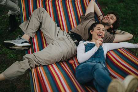 Young friends relaxing together on colorful hammock outdoors in a green park
