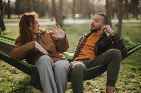 Young couple sharing a lively conversation while relaxing outdoors.の写真素材