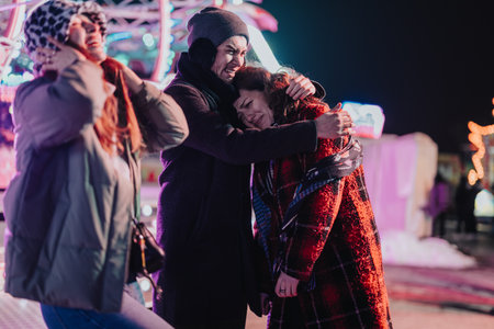 Group of friends embracing and laughing at a nighttime festive event