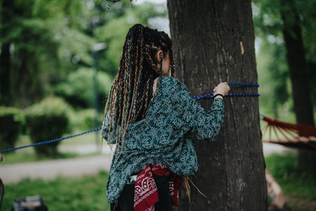 Woman setting up a hammock in a green park surrounded by trees