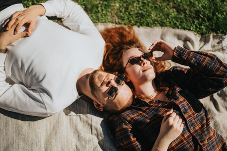 Relaxing couple enjoying a sunny day outdoors underneath sunglassesの写真素材