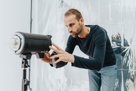Man adjusting professional studio lighting equipment in a creative workspace