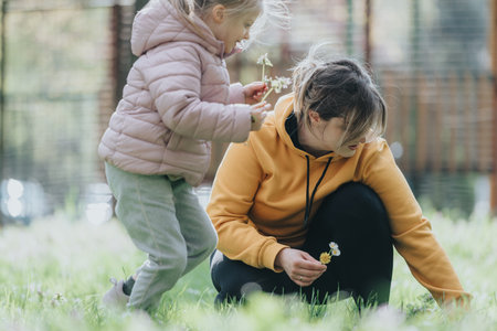 Mother and daughter spending time in a park picking flowers outdoors