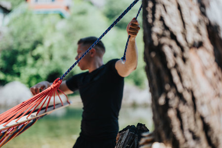 Person setting up a hammock beside a scenic riverside locationの写真素材