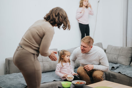 Family gathers together in the living room sharing moments and enjoying snacks.の写真素材
