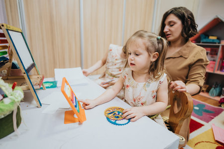 Mother Teaching Her Daughter at Home Using Educational Toolsの写真素材