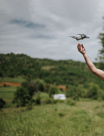 Man operating a drone in a scenic green outdoors landscapeの写真素材