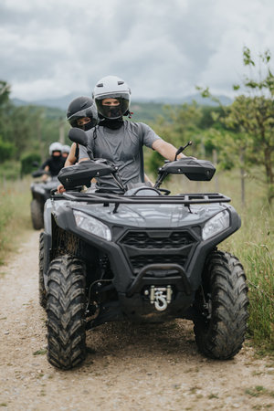 Two friends enjoying an adventurous ATV ride through scenic countryside terrainの写真素材
