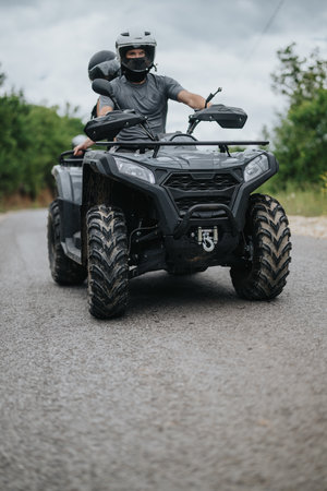 Two friends riding an ATV together on a scenic outdoor trailの写真素材