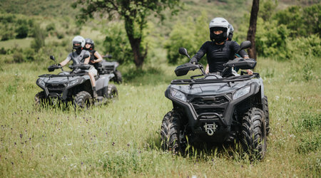 Group of friends riding quad bikes through a scenic grassy landscape