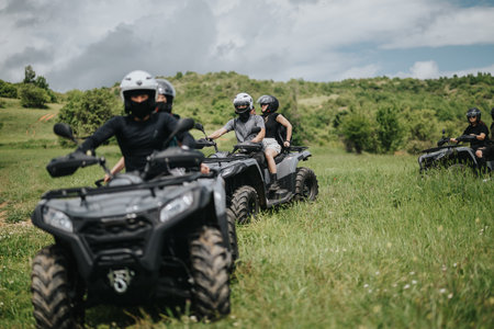 Group of friends riding quad bikes in a lush green countryside settingの写真素材