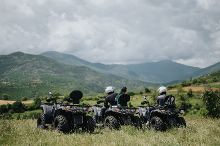 Group of friends enjoying a quad bike adventure in scenic hilly terrainの写真素材