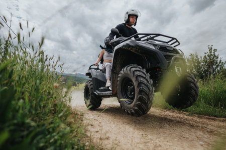 Two people riding an ATV through a dirt path in nature