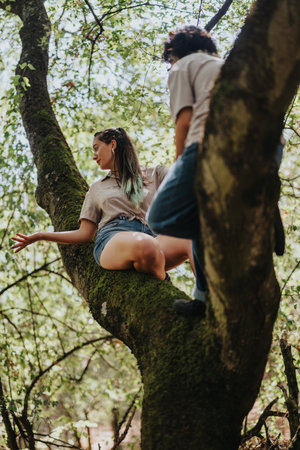 Two friends perched on a mossy tree branch, exploring the forest and enjoying nature together.の写真素材