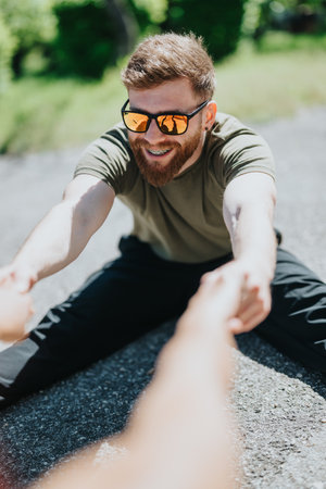 Smiling man in sunglasses enjoying a sunny day outdoors while stretchingの写真素材