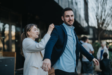 Colleagues adjusting attire in an outdoor business setting with casual atmosphereの写真素材