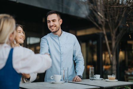 Colleagues meeting outdoors while enjoying coffee and greeting one anotherの写真素材