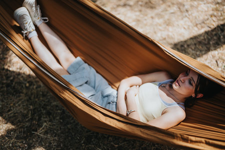 A woman lounges in a brown hammock outdoors on a sunny day