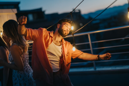 Friends enjoying a rooftop celebration under evening lights at sunsetの写真素材