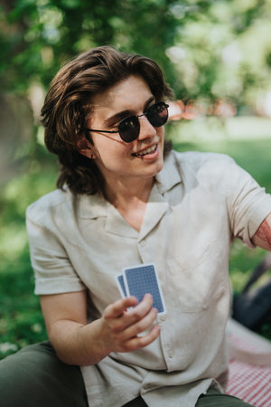 Young man playing cards outdoors in a sunny park