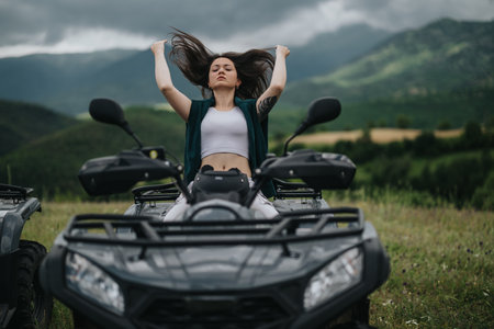 Woman on an all-terrain vehicle enjoying nature with dramatic mountain backdropの写真素材