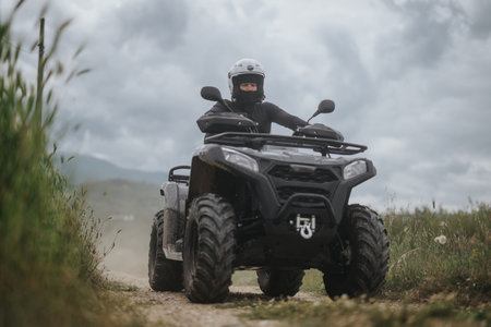 Person riding all-terrain vehicle on a dirt road amidst scenery