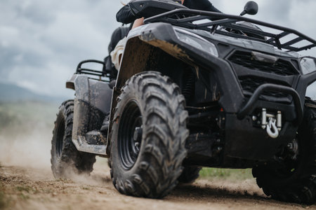 All-terrain vehicle riding on a rugged trail with dust and dirt flyingの写真素材