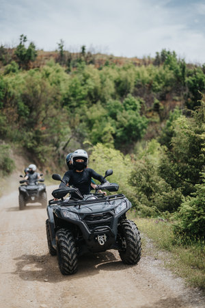 Group of friends riding quad bikes on a forest trail on a sunny day