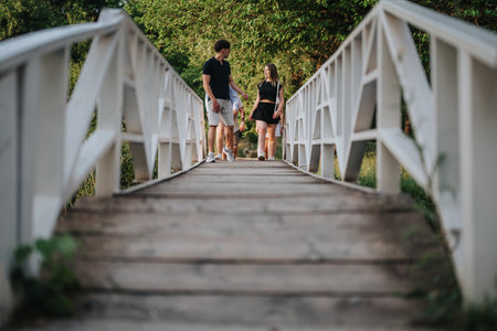 Couple walking along a picturesque wooden bridge in a park at sunsetの写真素材