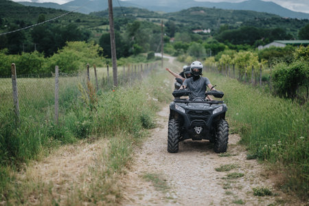 Two friends riding an ATV on a rural dirt road in nature