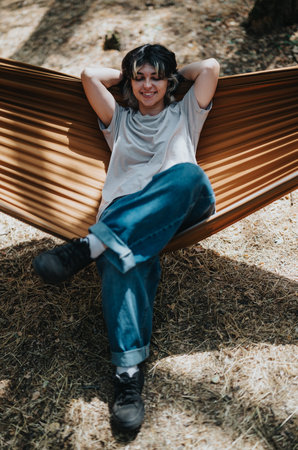 Woman relaxing in a hammock outdoors, enjoying a peaceful, casual afternoon in nature.