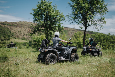 Group of friends riding quad bikes through a scenic countryside environmentの写真素材