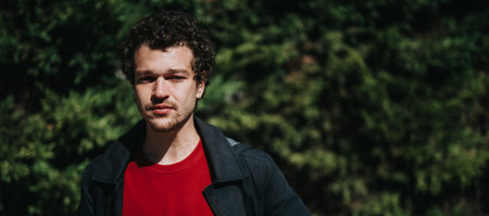Young man in a red shirt against a natural background outdoorsの写真素材