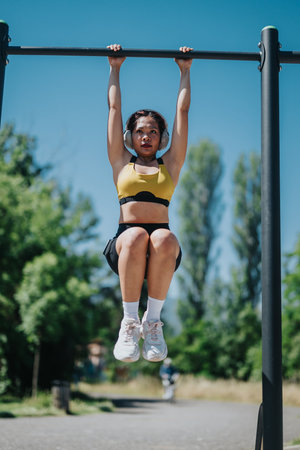 Young woman performing pull-ups in an outdoor park setting