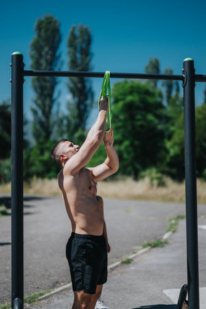 Man exercising with resistance band at outdoor fitness park on a sunny day