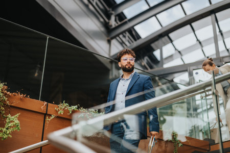 Confident professional walking in modern office building with glass architectureの写真素材