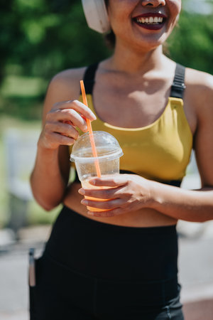 Woman enjoying a refreshment outdoors while listening to music in active wearの写真素材