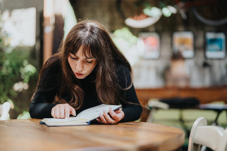 Young woman focused on reading a book at a cozy outdoor settingの写真素材