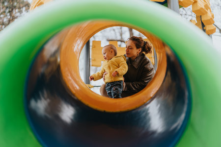 Mother and child playing at a colorful playground in autumnの写真素材