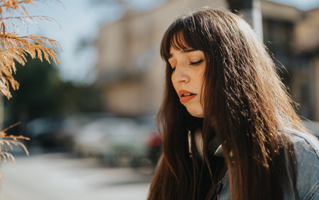 Young woman with serene expression in outdoor sunlight portraitの写真素材