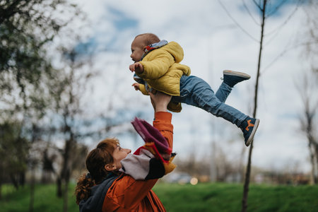 Mother lifting child outdoors on a bright and cheerful dayの写真素材