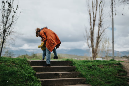 Mother assisting her child on green park steps during an outdoor strollの写真素材