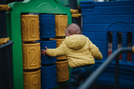 Child exploring a playground structure with colorful blocks on a calm dayの写真素材