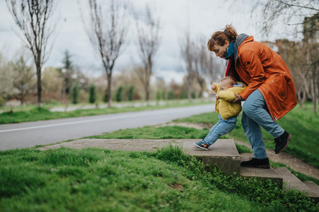 Mother guiding her child on outdoor steps in a serene park settingの写真素材