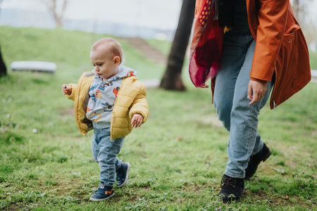 Young child walking with mother outdoors in a parkの写真素材