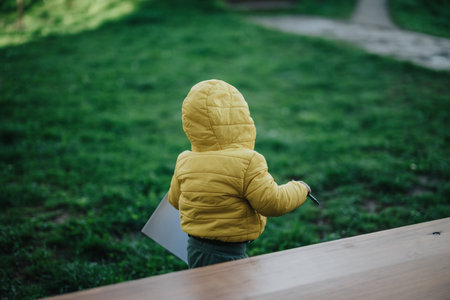 Child in yellow jacket outdoors on a grassy park fieldの写真素材