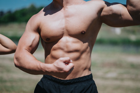 Muscular man flexing his arms showing strength and fitness outdoors