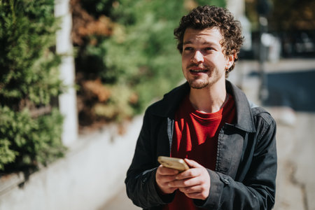 Man outdoors holding smartphone while expressing surprise and speaking energeticallyの写真素材