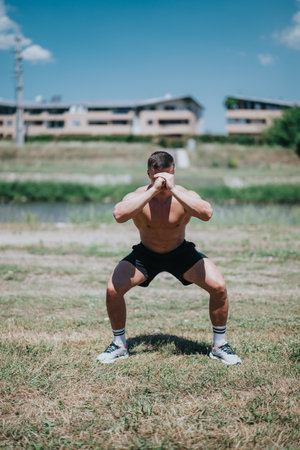 Man Performing Outdoor Squats During a Sunny Day in a Natural Settingの写真素材