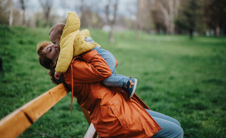 Mother enjoying playful moment with her child on a park benchの写真素材